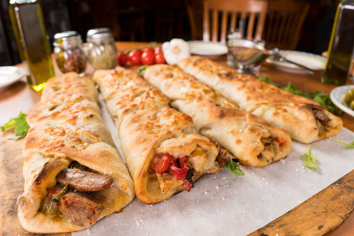 Assorted stromboli sliced open showing sausage, chicken, peppers and cheese