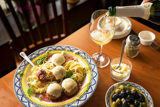 Spaghetti and meatballs with prosecco served family-style